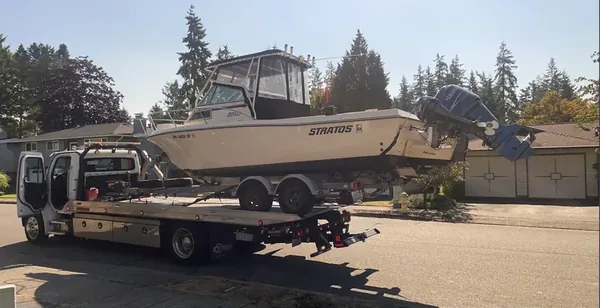 Boat on its trailer loaded onto a flatbed