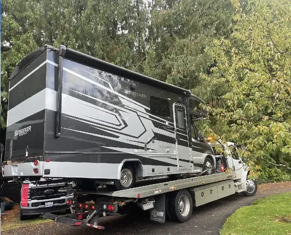 Class C motorhome loaded on a flatbed tow truck